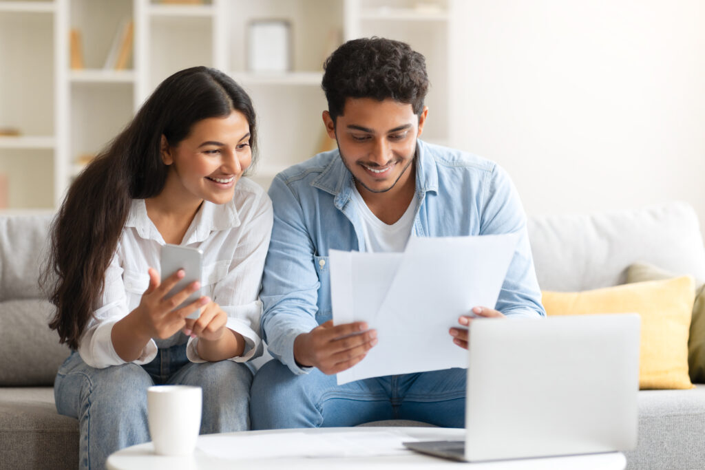 Young Indian couple reviewing document, with laptop and coffee